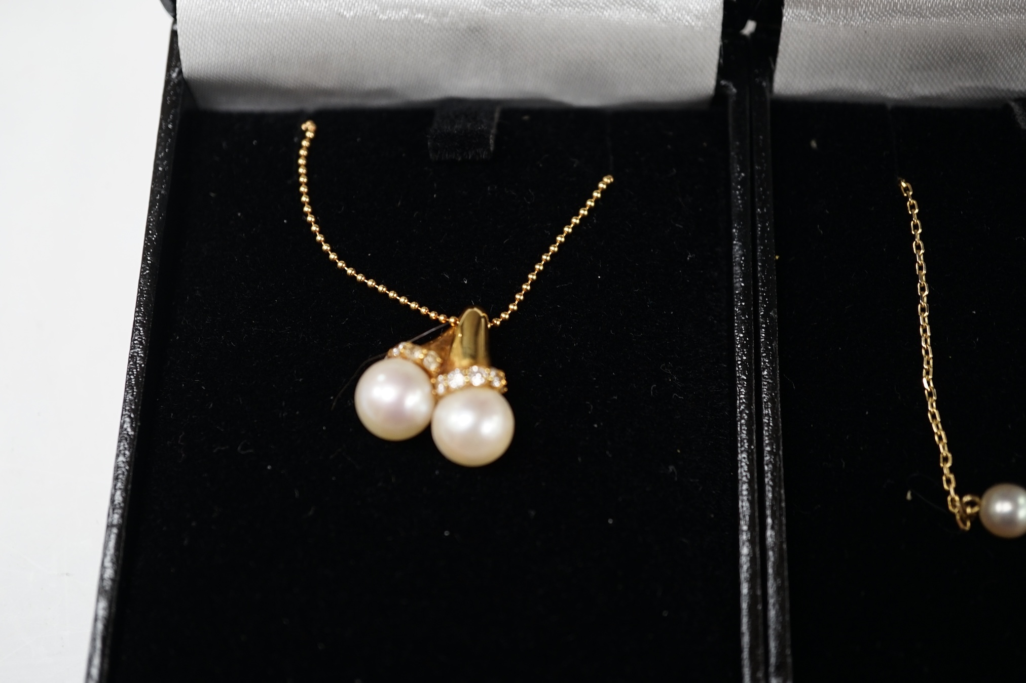 A modern 18k and two stone cultured pearl set pendant necklace, with diamond chip set collars, 42cm, gross weight 5.9 grams, together with a 14l and five stone cultured pearl set necklace, 35cm, gross weight 3 grams. Con